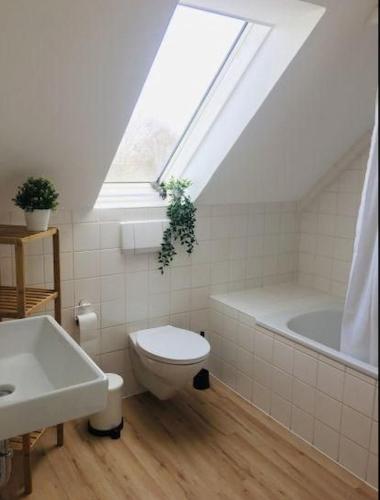 a white bathroom with a toilet and a bath tub at meerHAFEN in Orth