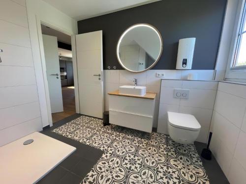 un bagno con lavandino, WC e specchio di Little Welcome a Petersdorf auf Fehmarn