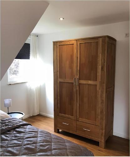 a bedroom with a wooden cabinet next to a bed at Little Welcome in Petersdorf auf Fehmarn