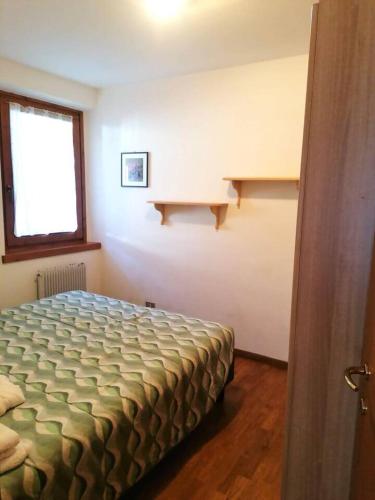 a bedroom with a bed and a window and shelves at MountainHome Garage and Free Parking in Bocenago