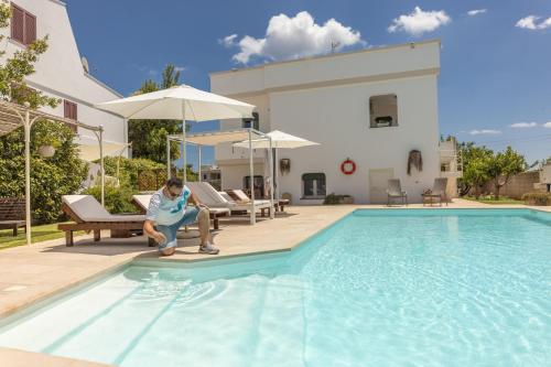ガリアーノ・デル・カーポにあるVilla Estro del Sudのスイミングプール横の椅子に座る男