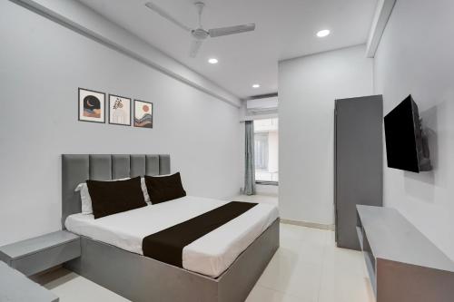 ein weißes Schlafzimmer mit einem Bett und einem Fernseher in der Unterkunft SPOT ON Hotel The Comfort Cove in Rānder