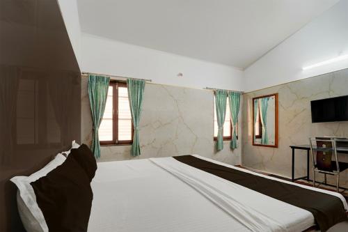 a bedroom with a large white bed with a television at Collection O Perumalmalai Bus Terminal Formerly Raja Garden Hill View in Kodaikānāl