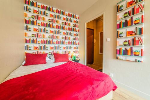 a bedroom with a red bed and a wall of books at L Icone de la Guierle - 1 Chambre in Brive-la-Gaillarde