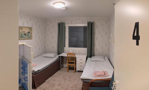 a small room with two beds and a desk at Pink Nissi in Kuusamo