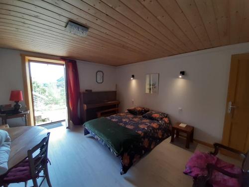 une chambre avec un lit, un bureau et une fenêtre dans l'établissement Coeur de Village du Haut-Jura, à Les Bouchoux