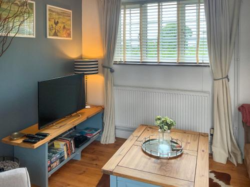 ein Wohnzimmer mit einem TV und einem Holztisch in der Unterkunft Archers Cottage in Birley