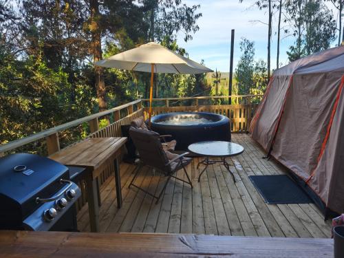 a deck with a hot tub and a table and an umbrella at Glamping Puertecillo Surf & Camp in Puertecillo