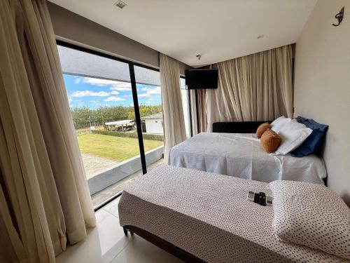 a bedroom with two beds and a large window at Águas da Serra in Bananeiras