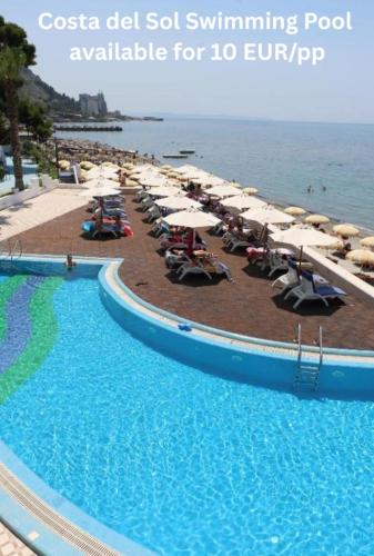 a swimming pool with chairs and umbrellas next to the ocean at Hill Side Suite by PS in Durrës