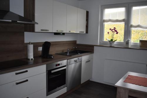 a kitchen with white cabinets and a sink and a window at Ferienwohnung Wiedergrün in Durbach