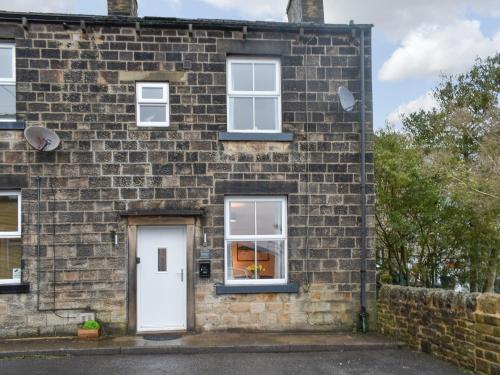 a brick house with a white door and windows at Prospect Cottage in Skipton