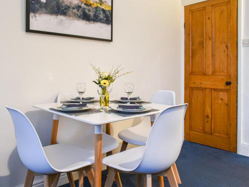 a white dining room with a white table and chairs at Prospect Cottage in Skipton