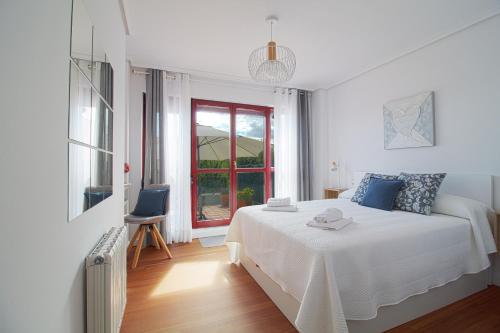 a white bedroom with a bed and a window at Apartamento Aventuras in Comillas