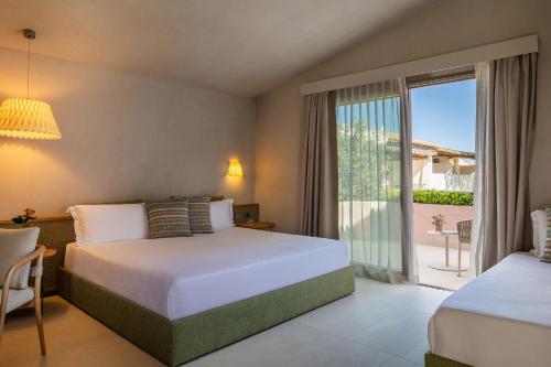 a bedroom with two beds and a large window at La Suera San Pantaleo in San Pantaleo