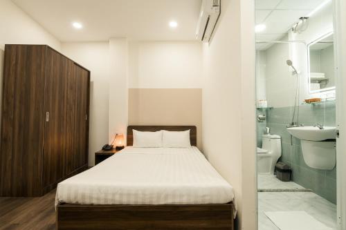Un dormitorio con una cama y un baño con lavabo. en Cashew Inn, en Ho Chi Minh
