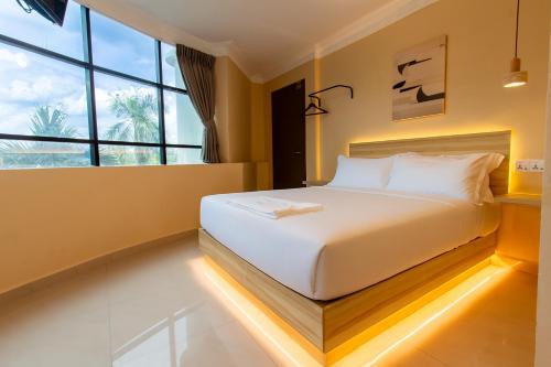 ein Bett in einem Zimmer mit einem großen Fenster in der Unterkunft Blenz Hotel in Serdang