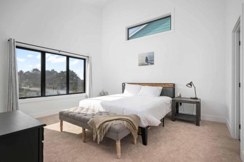 a white bedroom with a bed and a window at Lake & Laughter Unit 1 in Rockaway Beach