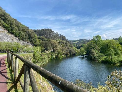Un río con una barandilla de madera al lado de un puente. en Casa Yito, en Muñorrodero