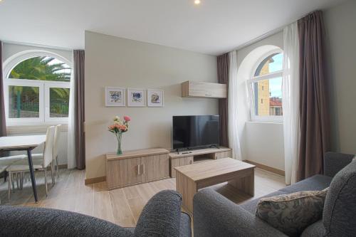 ein Wohnzimmer mit Sofa und Fernseher in der Unterkunft Apartamentos Turísticos La Pontificia in Comillas