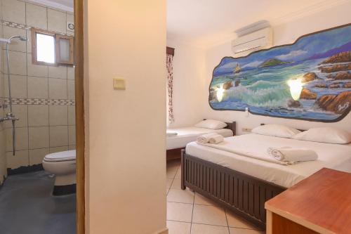ein Zimmer mit zwei Betten und ein Badezimmer mit Dusche in der Unterkunft Turunç Pansiyon in Bodrum City