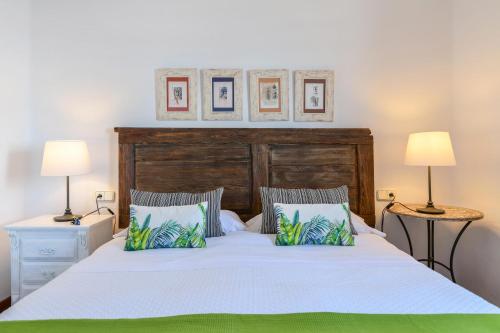 a bedroom with a bed with a wooden headboard and two lamps at Casa Vereda del Risco in Guinate