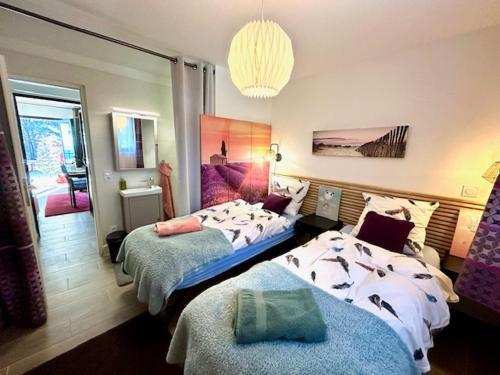 Un dormitorio con dos camas y una lámpara de araña. en Résidences des Peyrons vue exceptionnelle mer et sur les Iles d'Or, en Carqueiranne