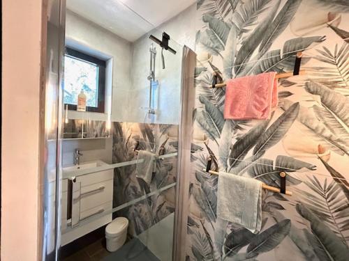 y baño con ducha y papel pintado tropical. en Résidences des Peyrons vue exceptionnelle mer et sur les Iles d'Or, en Carqueiranne