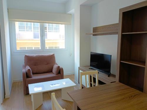 ein Wohnzimmer mit Sessel und Fernseher in der Unterkunft Marynton Boutique in Benicarló