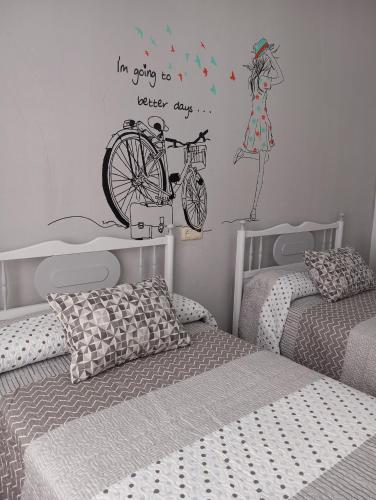 a bedroom with two beds and a bicycle on the wall at El descanso soberano in Ossa de Montiel