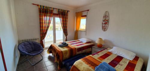 a bedroom with two beds and a chair and a window at Villa Jopati in Olho Marinho