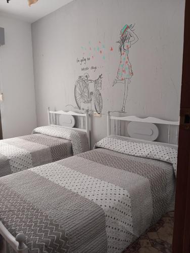 a room with three beds and a painting on the wall at El descanso soberano in Ossa de Montiel