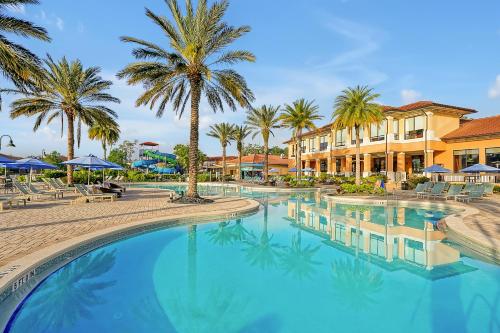 a large swimming pool with palm trees and buildings at Regal Oaks Resort Vacation Townhomes by IDILIQ in Orlando