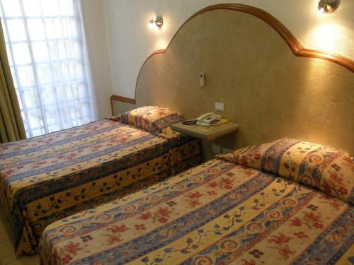 a hotel room with two beds and a telephone at Hotel Fenix in Tapachula