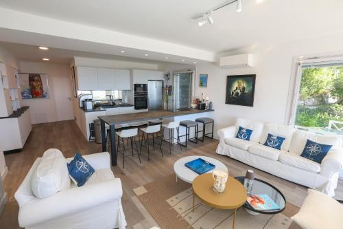 a living room with white furniture and a kitchen at Appartement exception les pieds dans l'eau in Èze