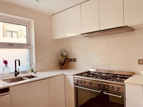 a kitchen with white cabinets and a stove top oven at London loft by let it b travel in London