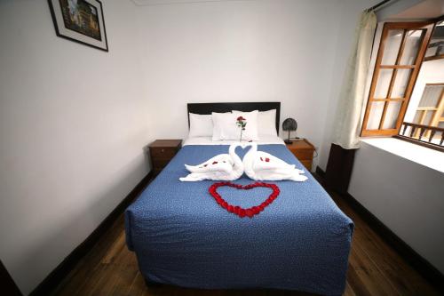 1 cama con 2 toallas en forma de corazón en Hostal el Conquistador, en Cusco