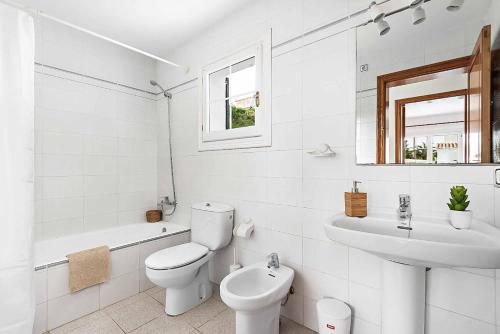 a white bathroom with a toilet and a sink at Villa Cala Llonga in Cala Llonga