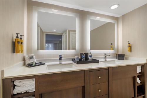 a bathroom with two sinks and two mirrors at Best Western Plus Carriage Inn in Sherman Oaks