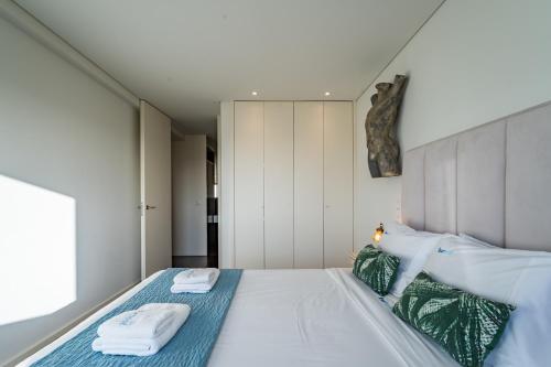 a bedroom with a bed with towels on it at Sun, Sea, and Comfort Apartment in São Félix da Marinha