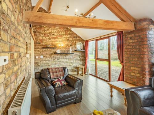 a living room with a leather chair and a brick wall at The Tack Rooms - Uk37520 in Routh