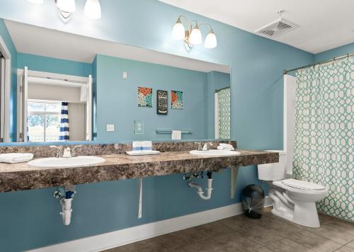 a blue bathroom with two sinks and a toilet at Experience comfort at Quill Haven - Pet Friendly in Grand Haven
