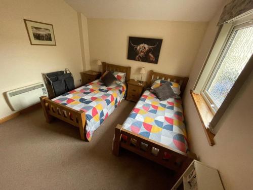 ein Schlafzimmer mit zwei Betten und einem Fenster in der Unterkunft Hopeman Cottages in Hopeman