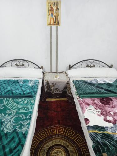 a room with two beds and a rug at Sun Rise House Luxor in Al Aqālitah