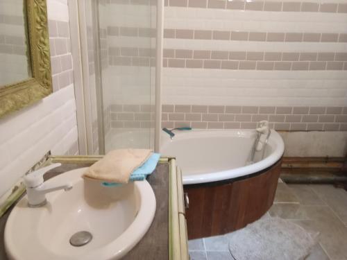 a bathroom with a tub and a toilet and a sink at La Grille Fleurie, chambres d'hôte chez l'habitant in Arthonnay