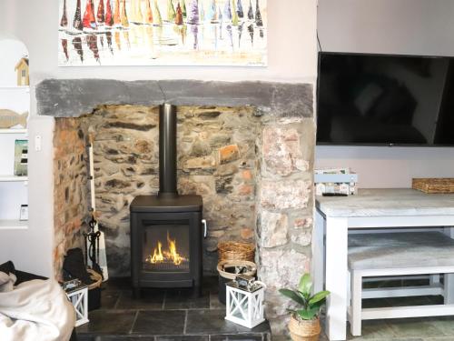 a stone fireplace in a living room with a tv at Cwrt in Dwyran