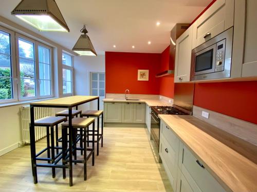 une cuisine avec des murs rouges et un comptoir avec des tabourets dans l'établissement LANOISELEE, à Saint-Honoré-les-Bains