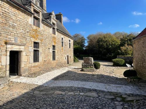 an old brick building with a stone path next to it at Manoir de Kerenneur in Plourin