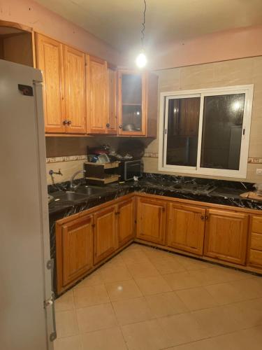 a kitchen with wooden cabinets and black counter tops at Villa dar deyafa jamaat fedalat in Sidi Moussa Ben Ali