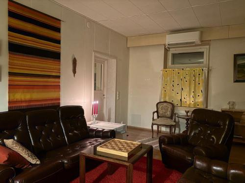 a living room with leather couches and a table at 60m2 studio w sauna in a semi-detached house in Lapinkangas in Oulu